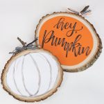 Image contains two wood slice pumpkin crafts.