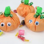 Image contains three pumpkin treat packs and assorted loose candy.