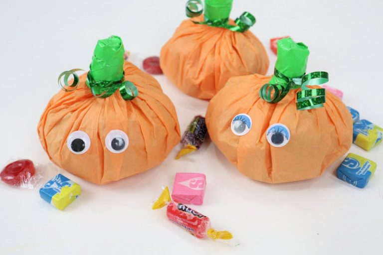 Image contains three pumpkin treat packs and assorted loose candy.