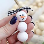 Image contains a snowman ornament made from white wood beads.