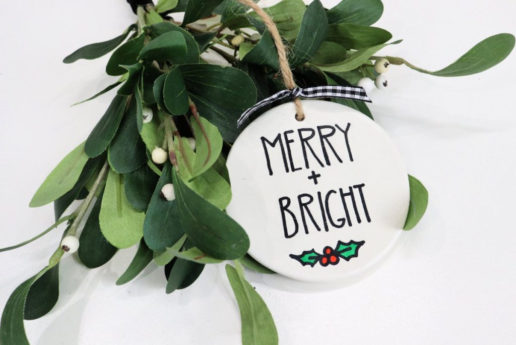 Image contains a white hand-lettered ornament and mistletoe.
