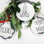 Image contains three white hand-lettered ornaments and mistletoe.