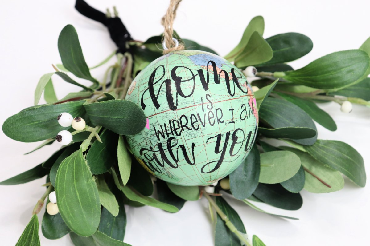 Image contains a green globe ornament labeled, "home is wherever I am with you," and mistletoe.
