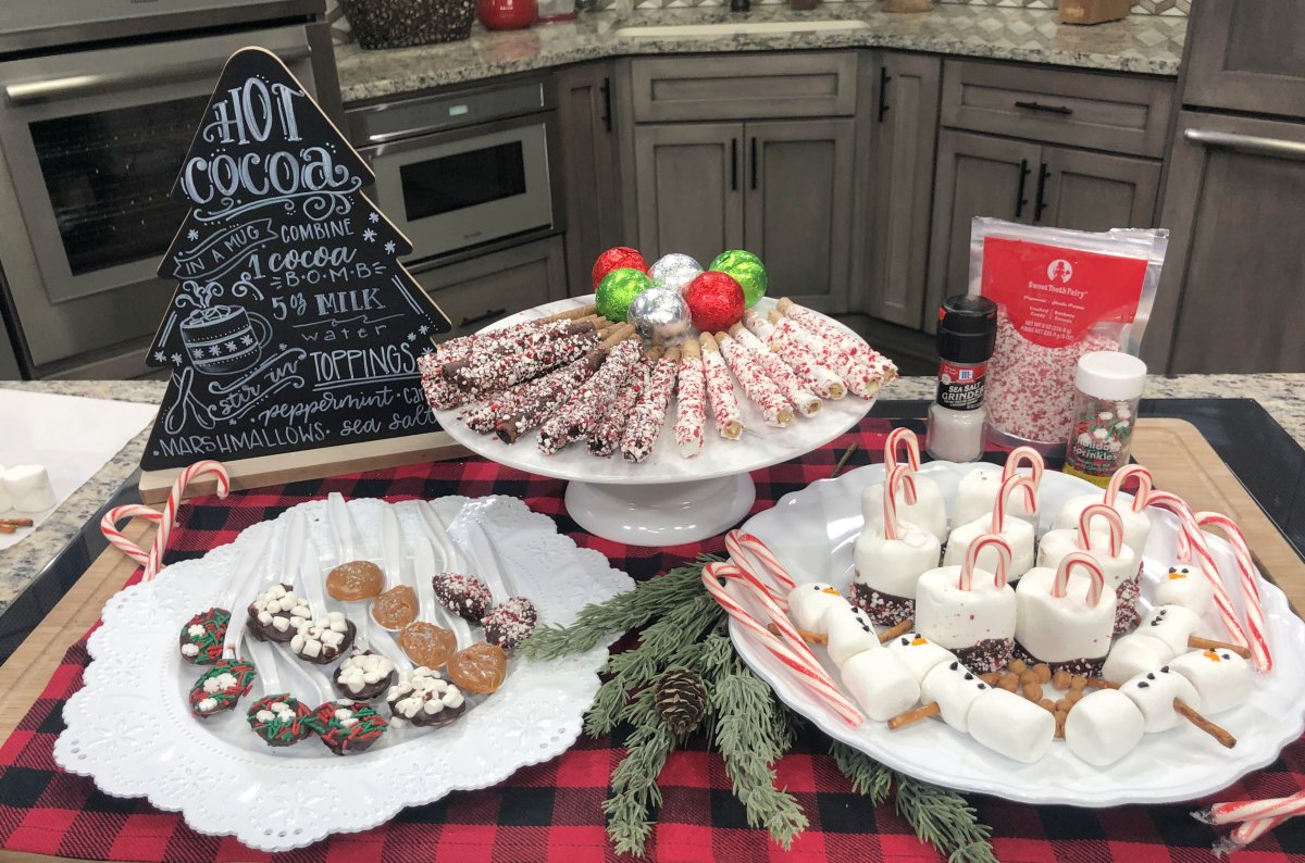 Image contains a hot chocolate bar display with a chalkboard sign and assorted treats.