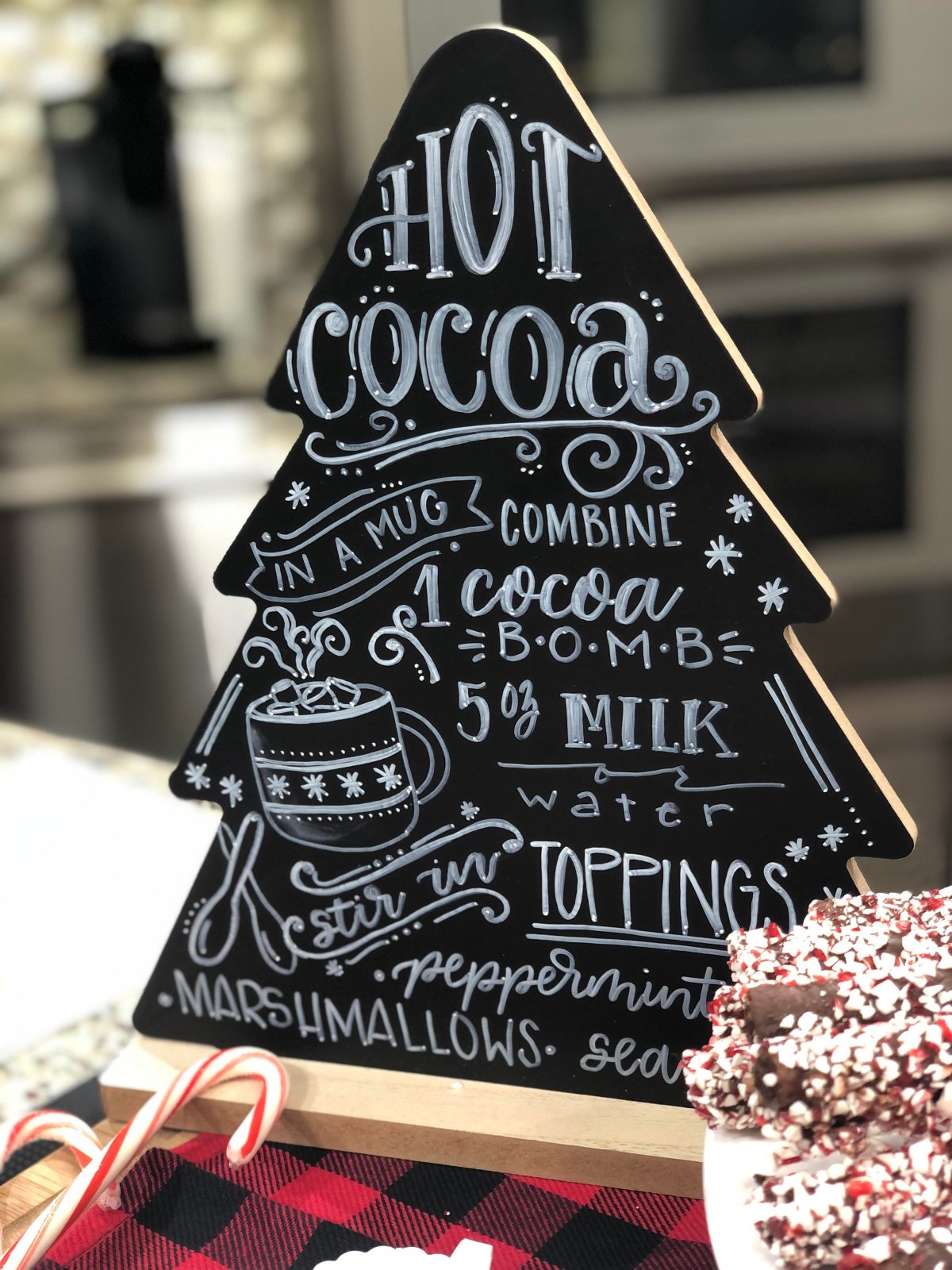 Image contains a tree shaped chalkboard sign about hot cocoa.