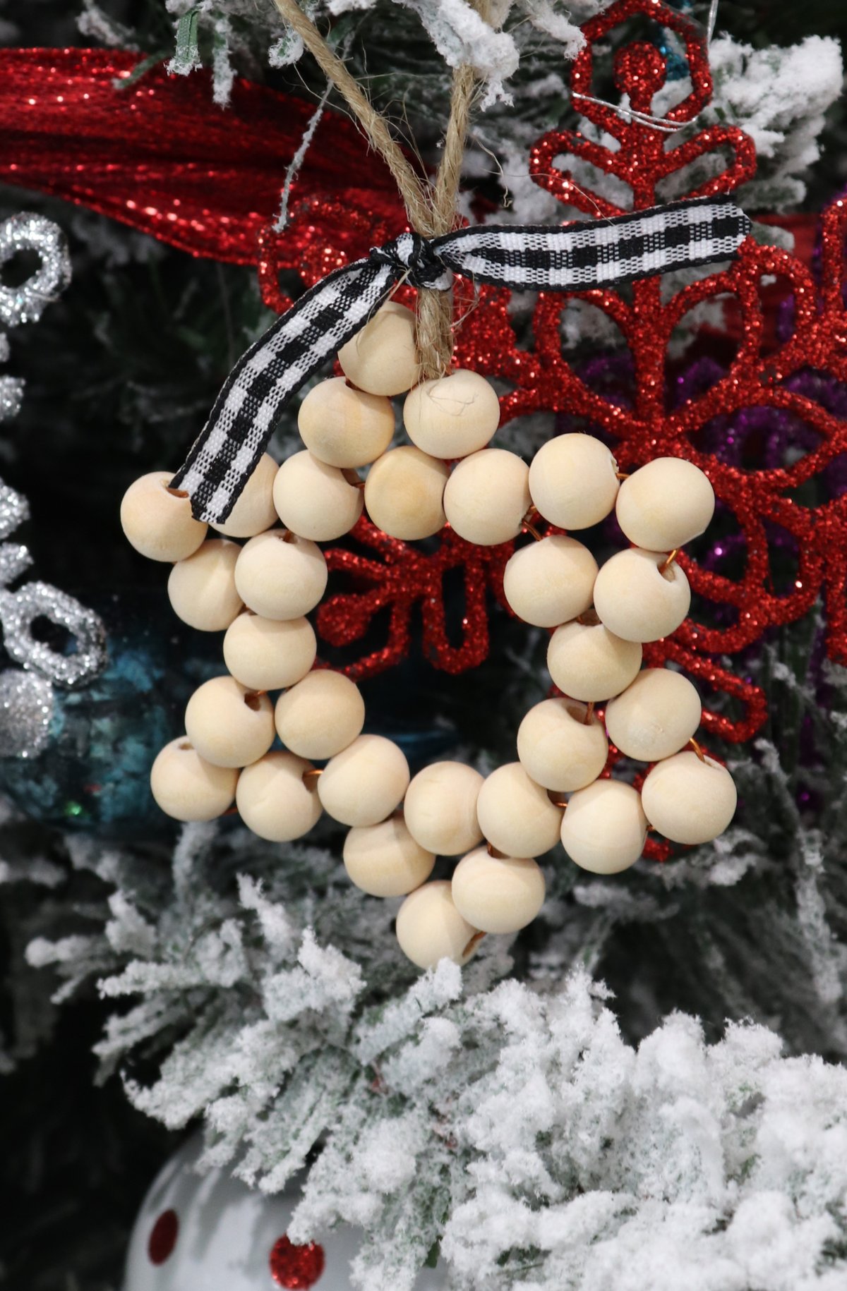 Image contains a wooden bead ornament in the shape of a six pointed star hanging on a tree.