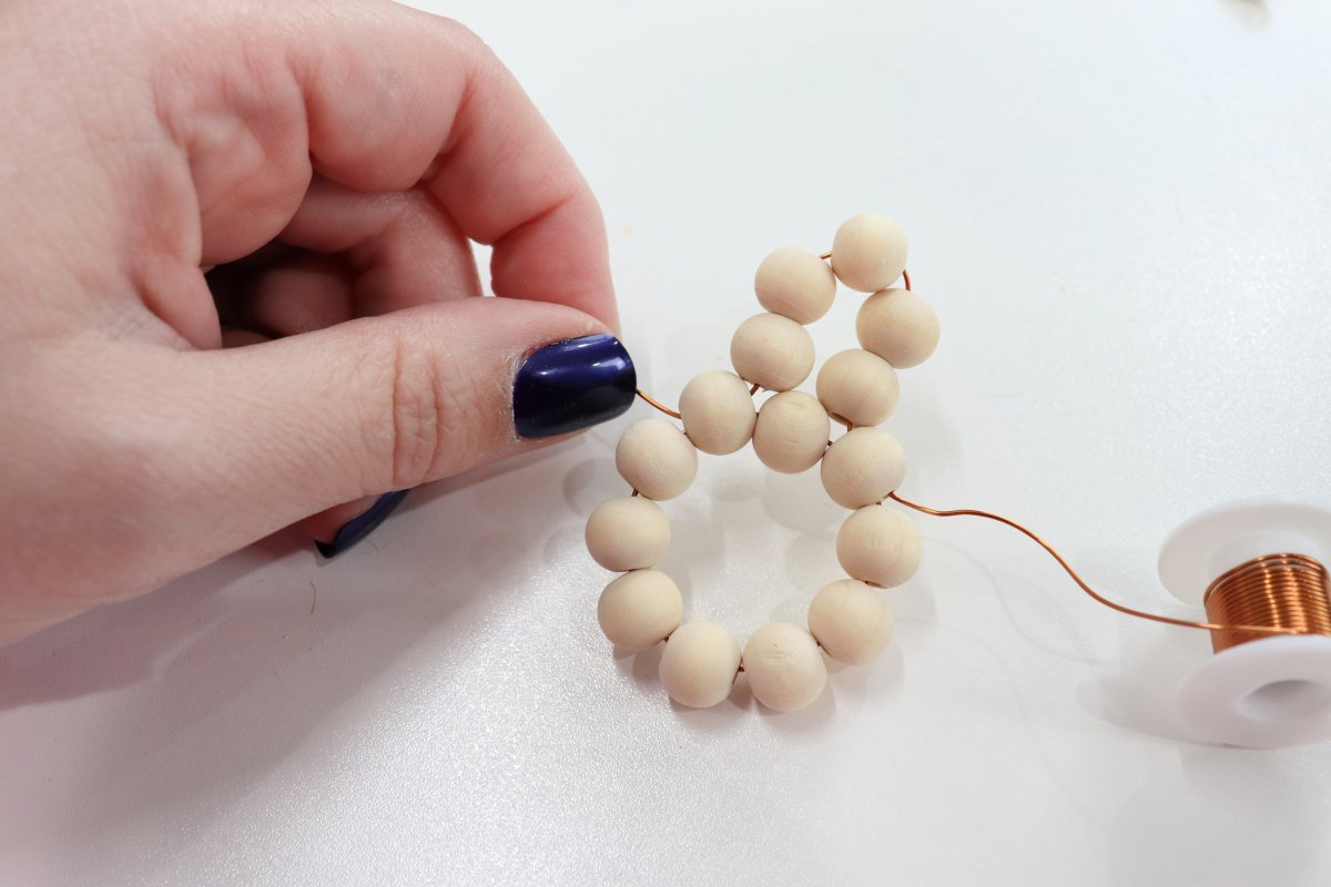 Image contains a hand holding wooden beads strung on wire.