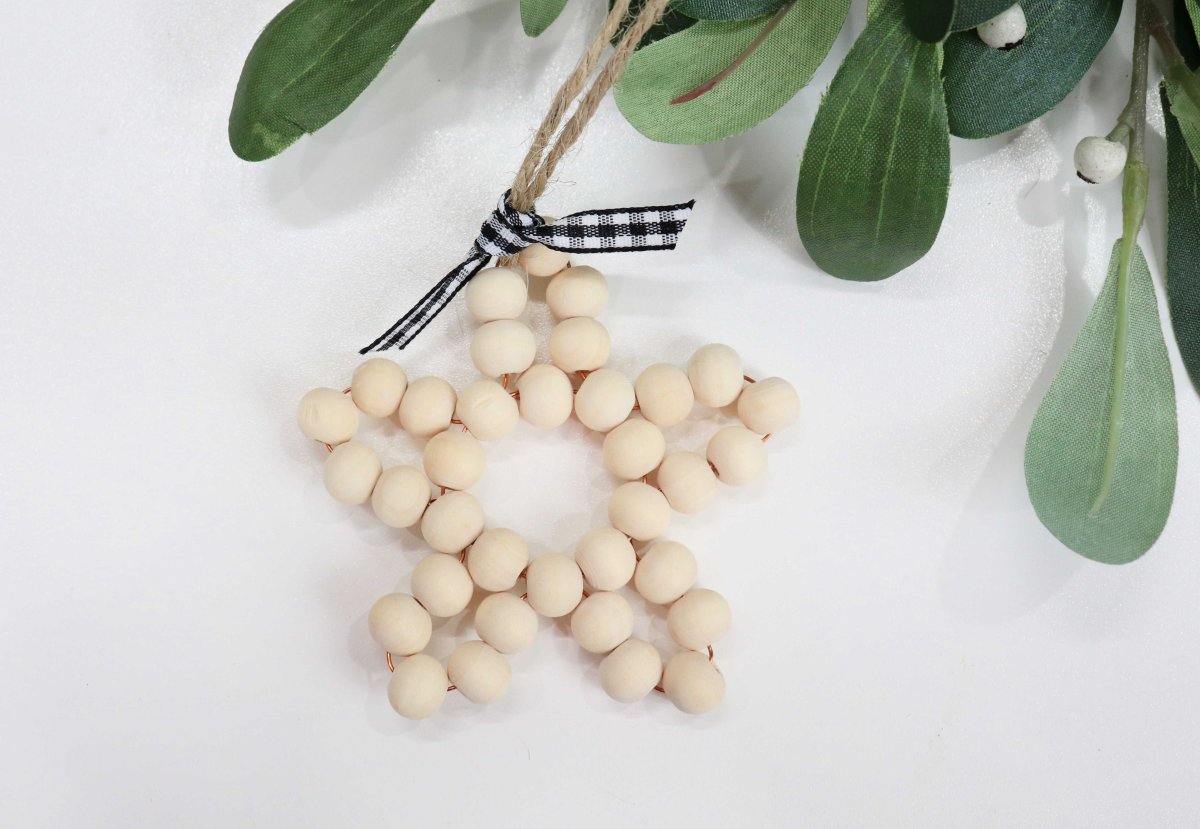Image contains a wooden bead ornament in the shape of a five pointed star, and mistletoe.