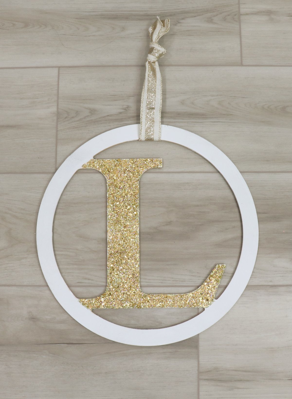 Image contains a large wooden monogram painted white and gold.