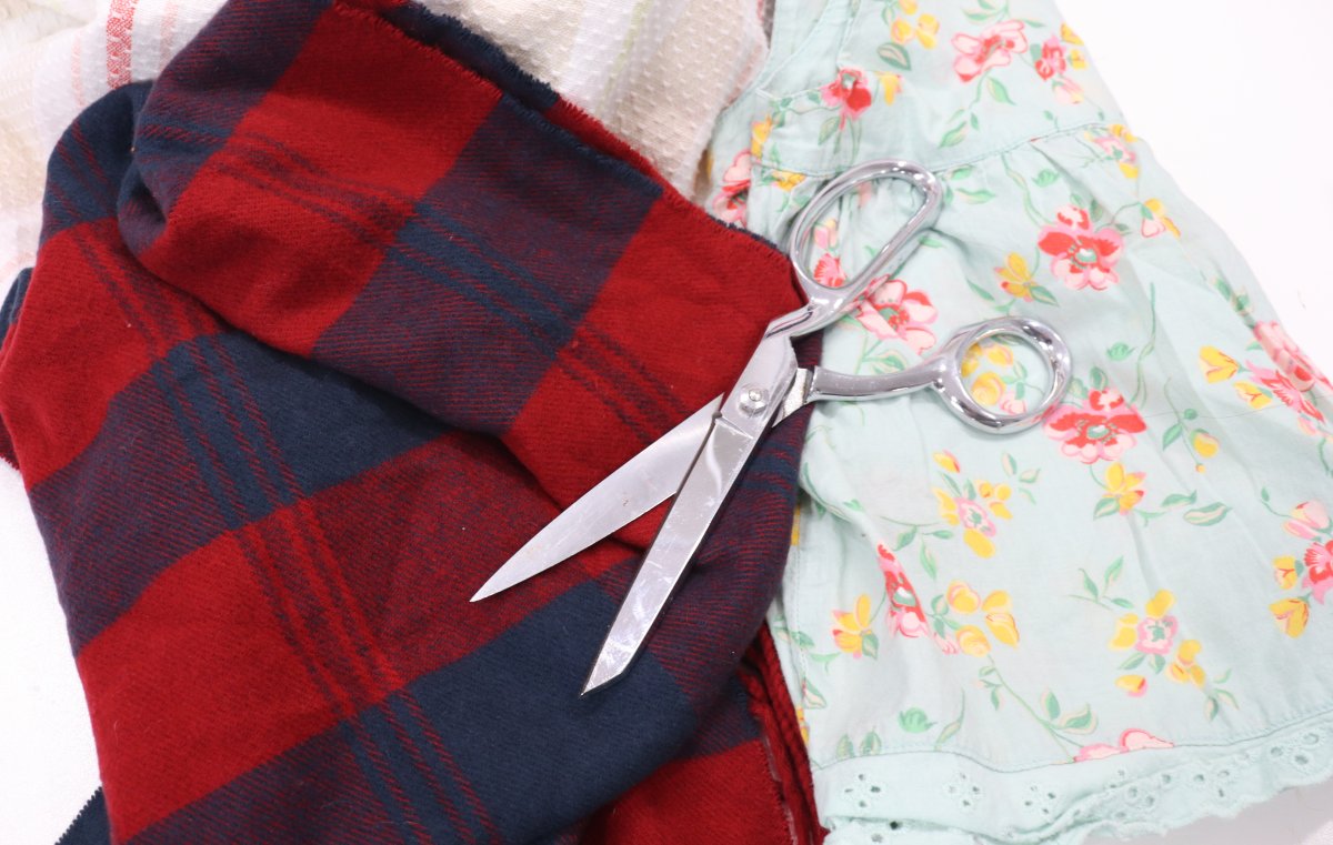 Image contains assorted fabric with a pair of scissors on top.