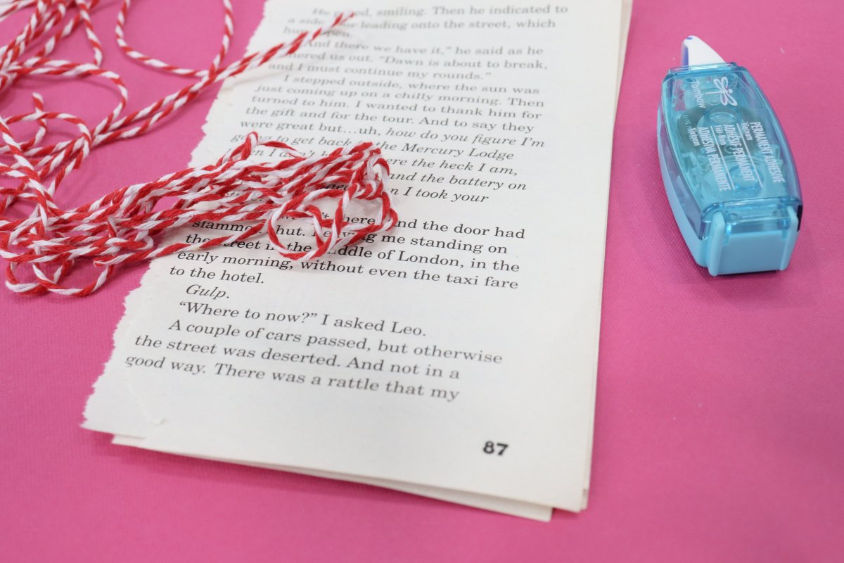 Image contains red and white twine, book pages, and an adhesive runner on a pink background.