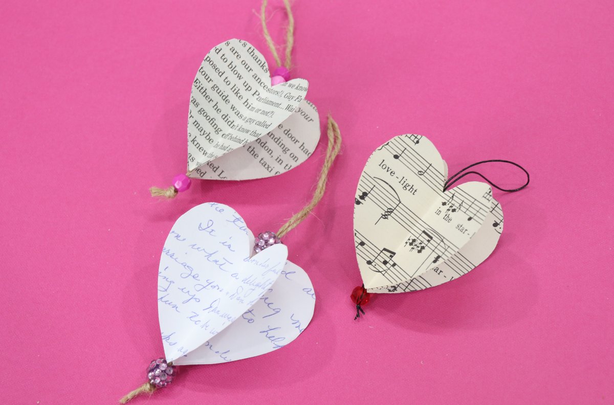 Image contains three 3-D paper hearts on a pink background.