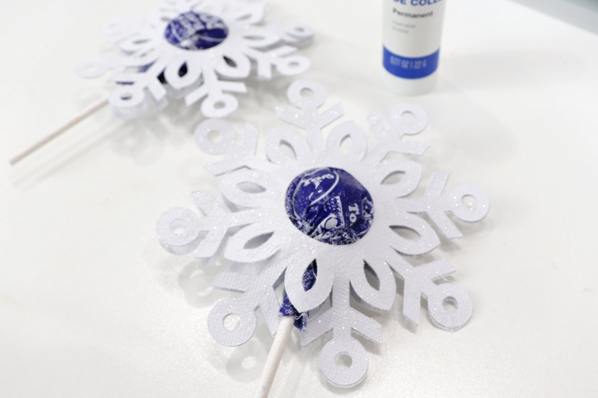 Image contains two decorative snowflake lollipops and a glue stick.