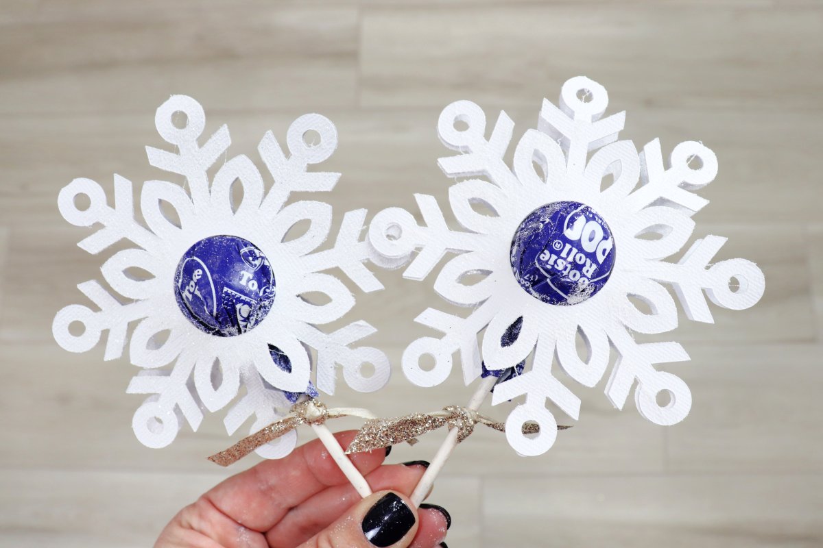 Image contains a hand holding two lollipops with snowflake borders.