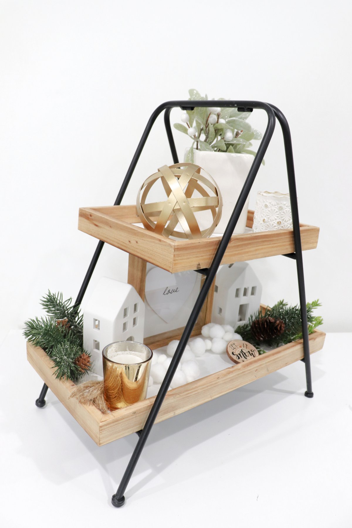 Image contains a decorative two-tiered tray styled for winter with white, green, and gold accents.