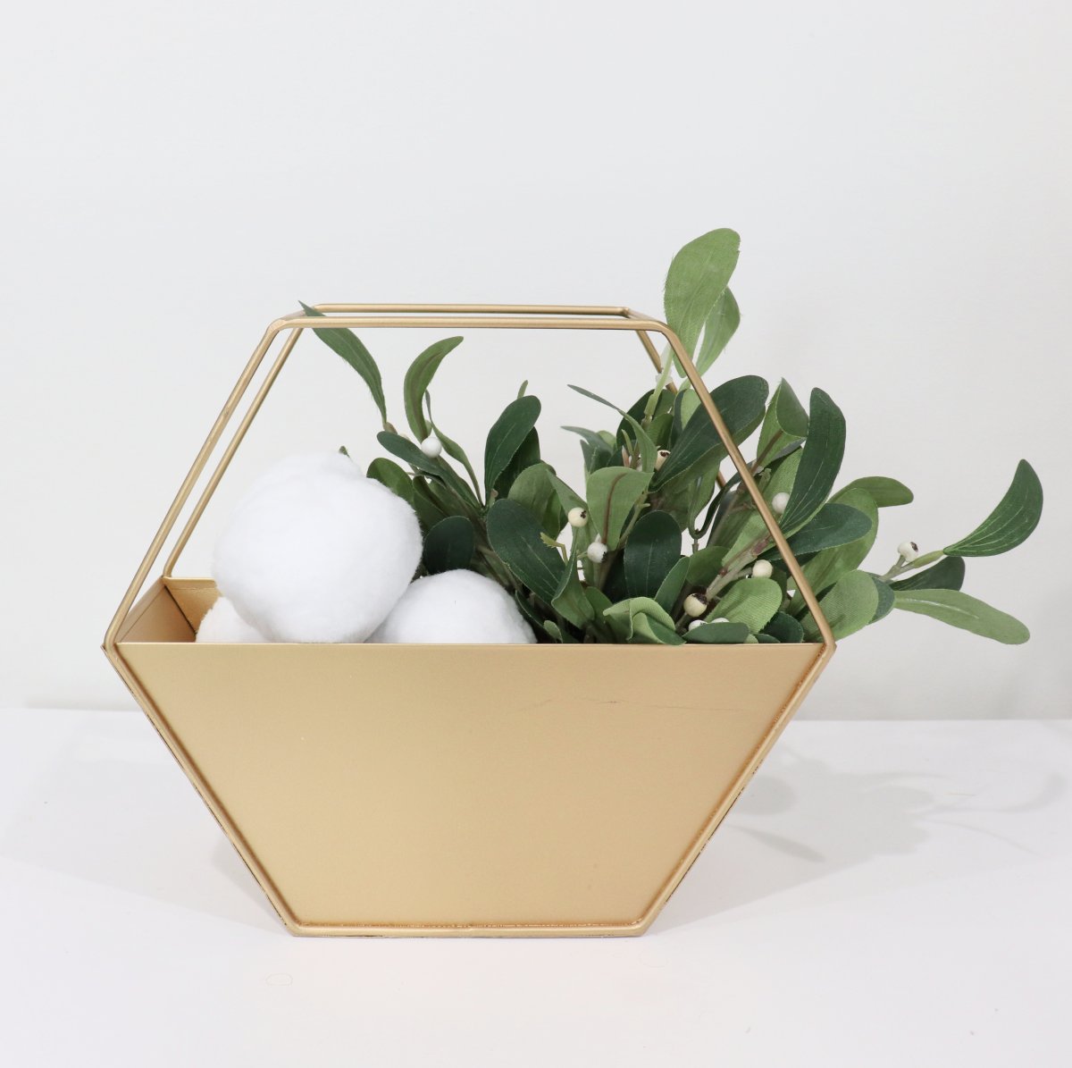 Image contains a hexagonal gold container with mistletoe and large snowballs.
