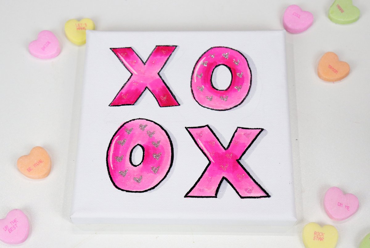 Image contains a square canvas with pink "xo" letters, and candy hearts.