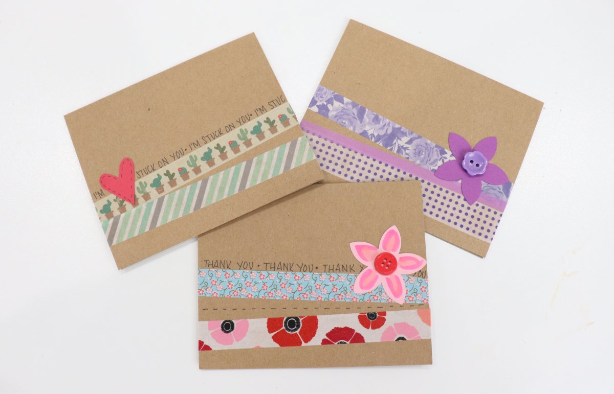 Image contains three handmade cards decorated with strips of washi tape and colored cardstock embellishments on a white background.