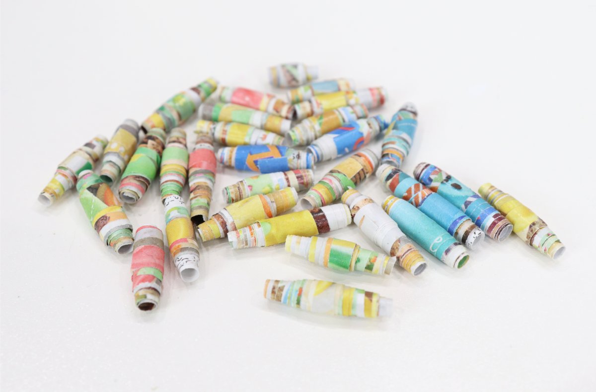 Image contains an assortment of rolled paper beads in a variety of colors on a white background.