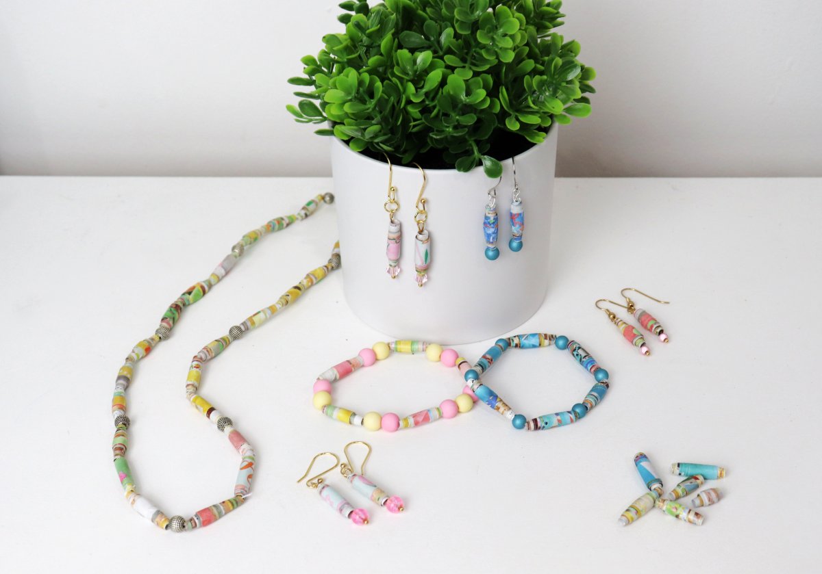 Image contains a necklace, two bracelets, and four pairs of dangle earrings made from paper beads.