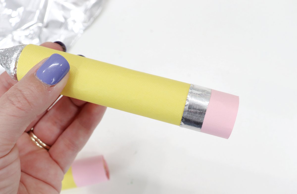Image contains Amy's hand holding a roll of Rolo candies wrapped in yellow and pink cardstock and aluminum foil to look like a pencil.