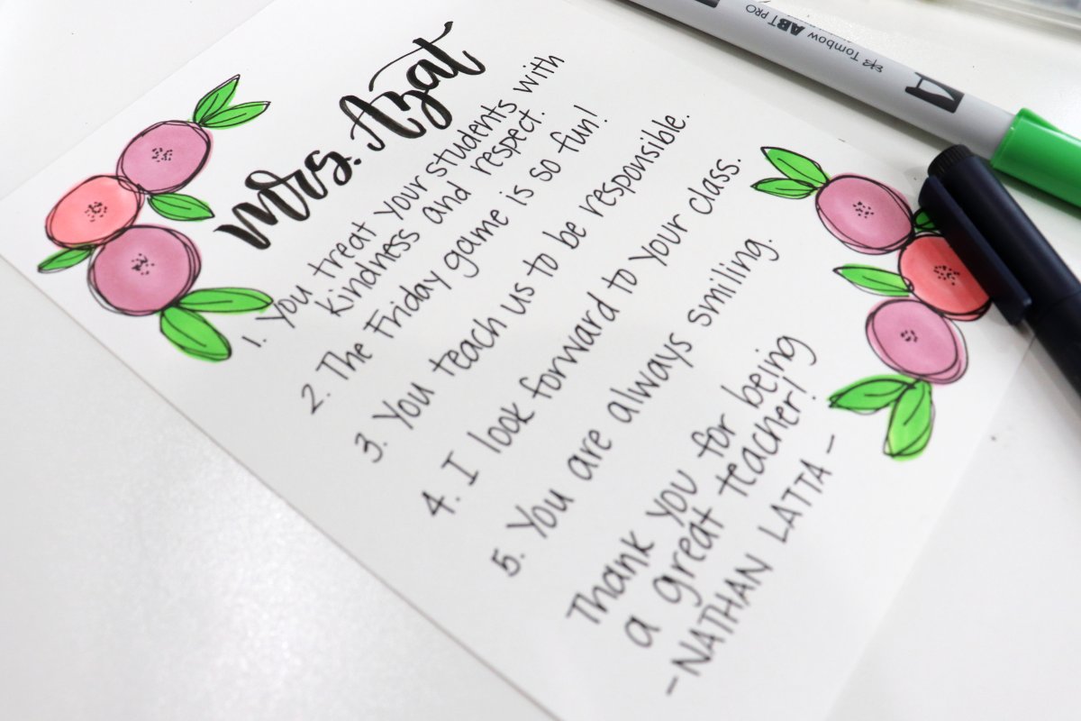 Image contains a piece of paper decorated with pink flowers and green leaves, with words describing five reasons a student likes his teacher.