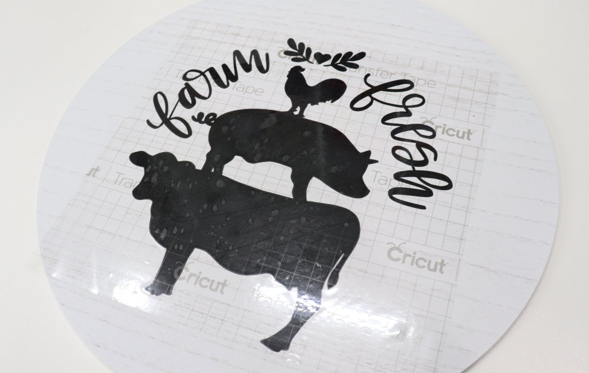 Image contains the "farm fresh" decal in black vinyl attached to a white wood circle with clear transfer tape.