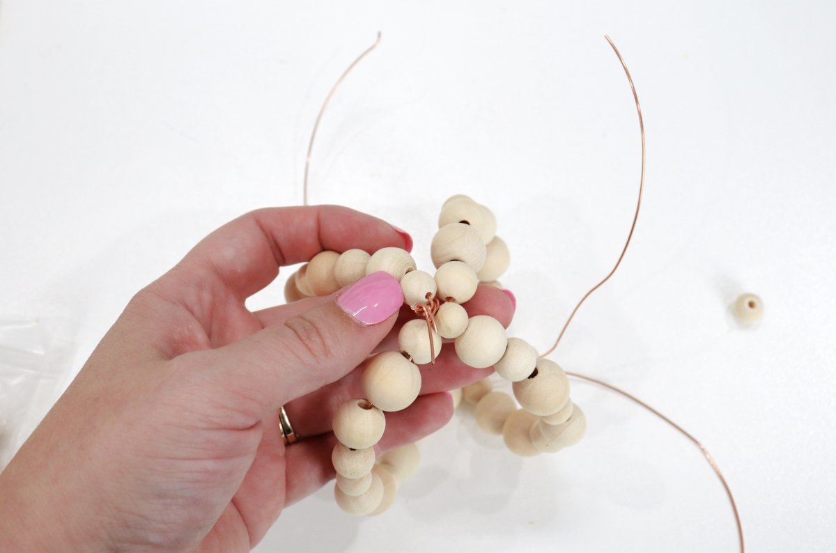 Image contains Amy's hand holding four strands of wooden beads with wire in the background.