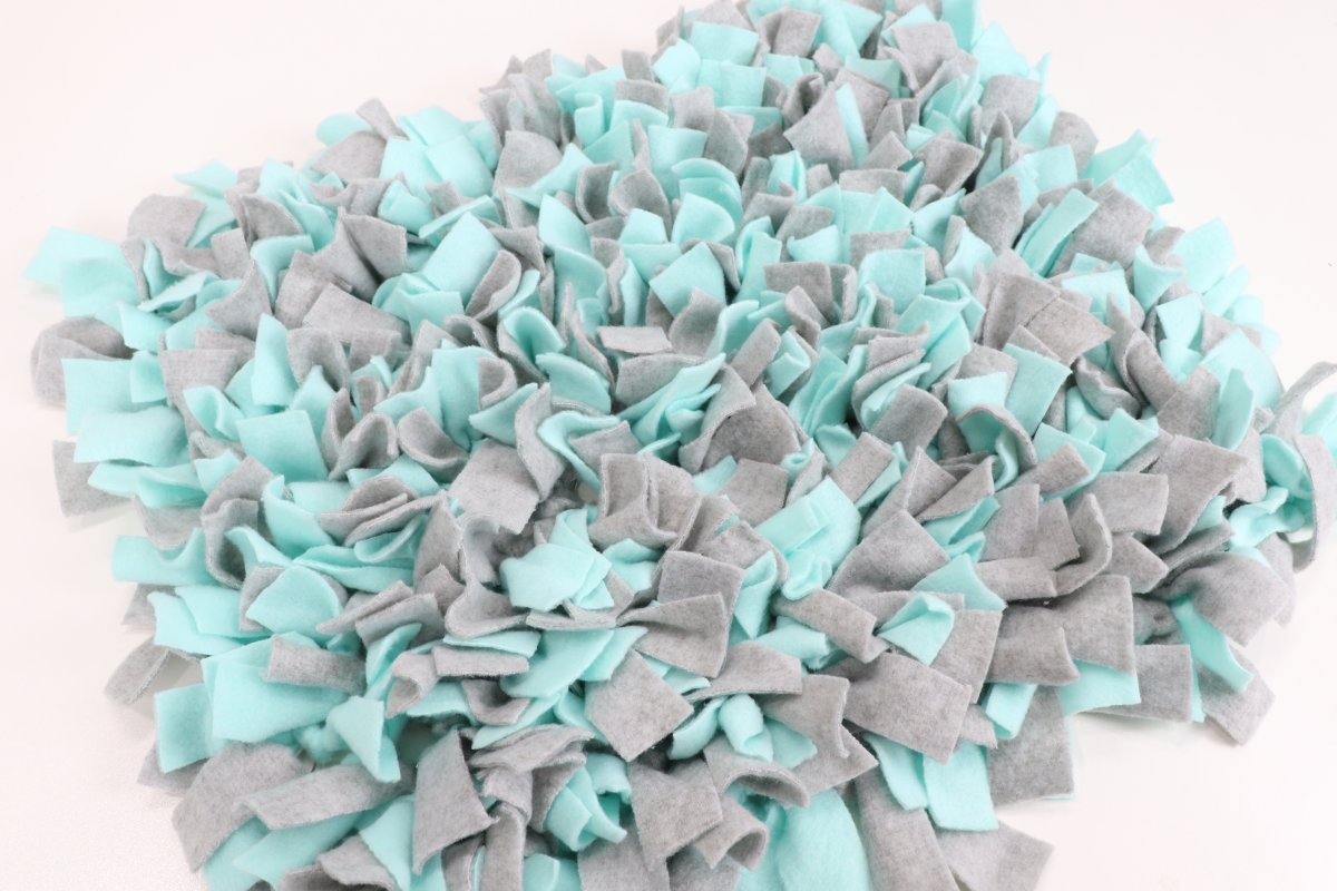 Image contains a teal and gray snuffle mat for dogs made of fleece.