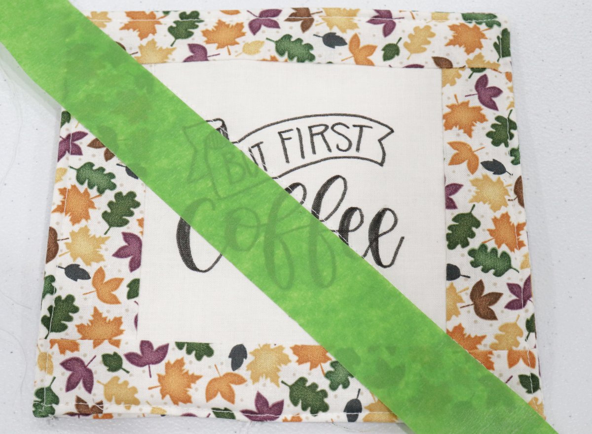 Image shows a fabric coaster with a piece of green masking tape placed across it diagonally.