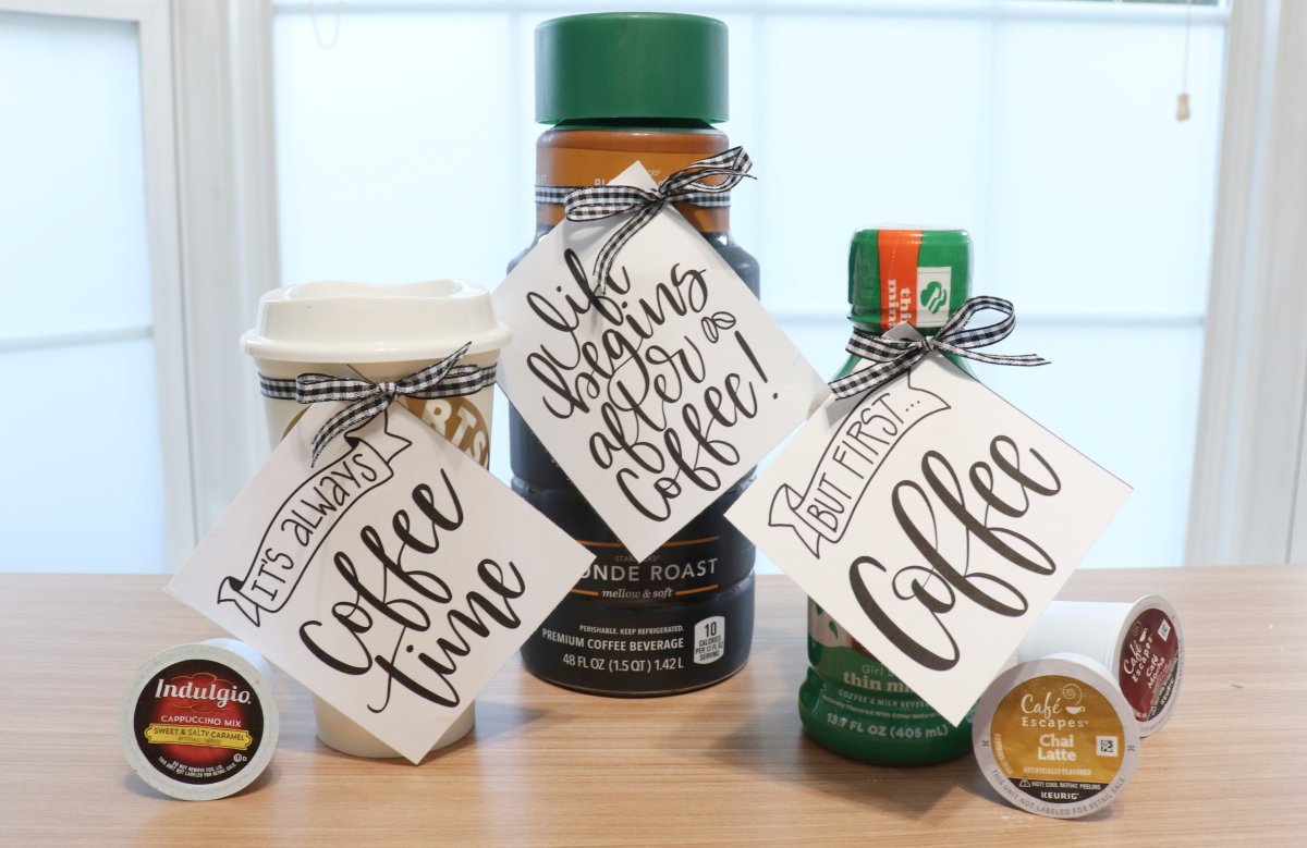 Image contains two bottles of iced coffee and a to-go cup, all with a hand lettered label attached. The labels have sayings about coffee hand lettered in black.