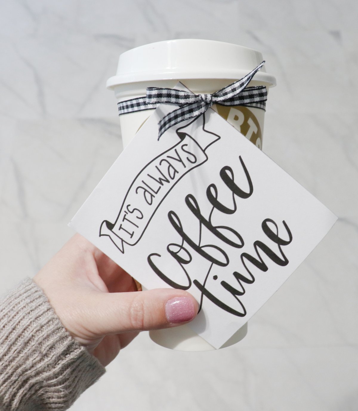 Image contains Amy's hand holding a to-go cup with a label that reads, "it's always coffee time." The label is attached with black and white ribbon tied in a bow.