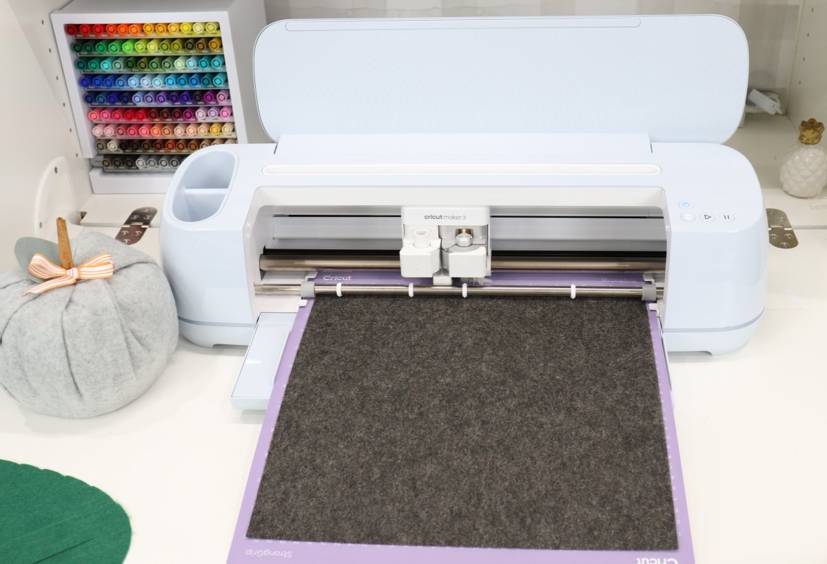 Image contains a Cricut Maker 3 loaded with grey felt.