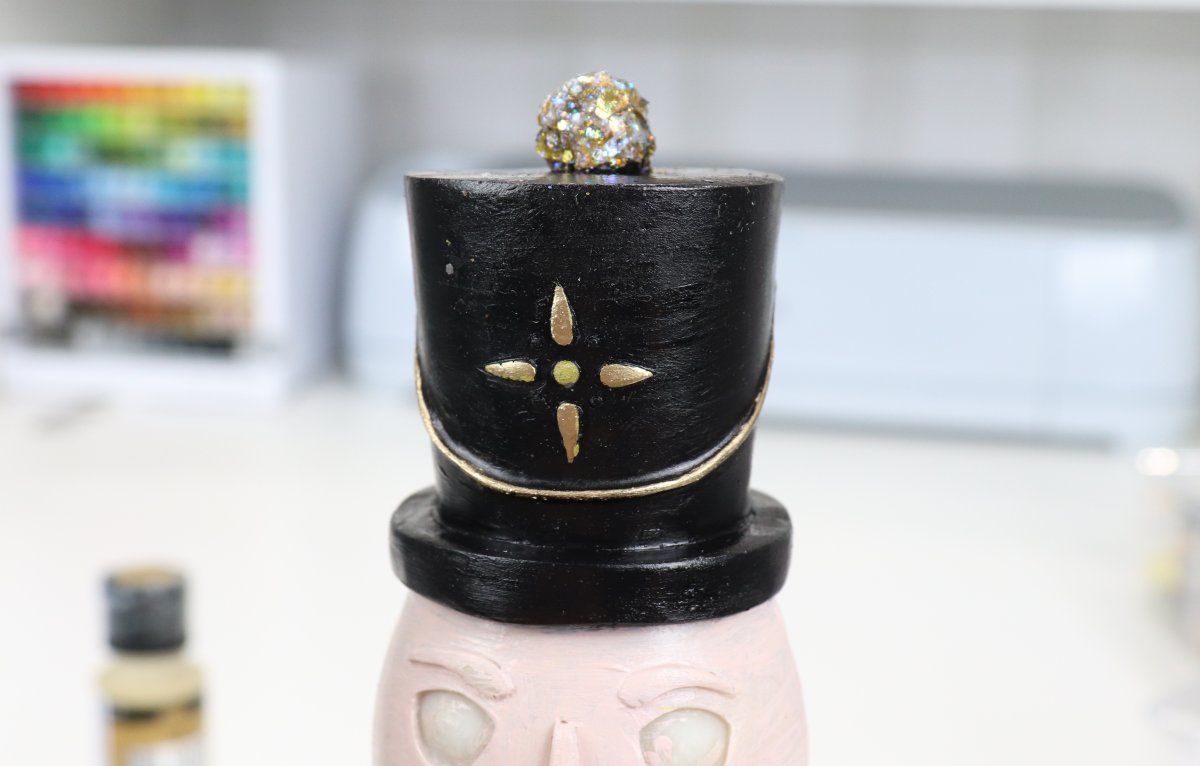Image contains a closeup of the nutcracker figure's black hat with gold detailing.