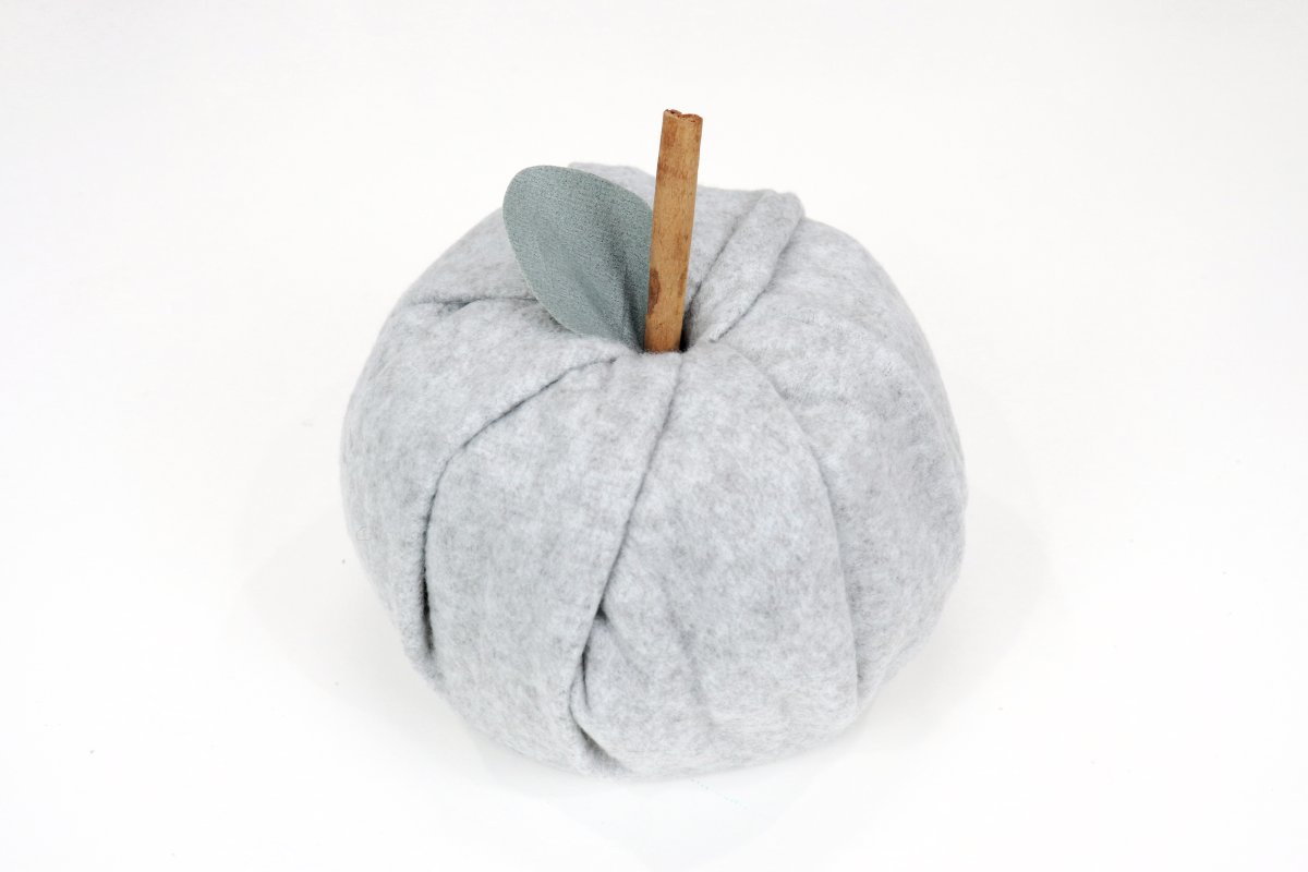 Image contains a pumpkin made of grey fleece with a cinnamon stick stem and a faux leaf.