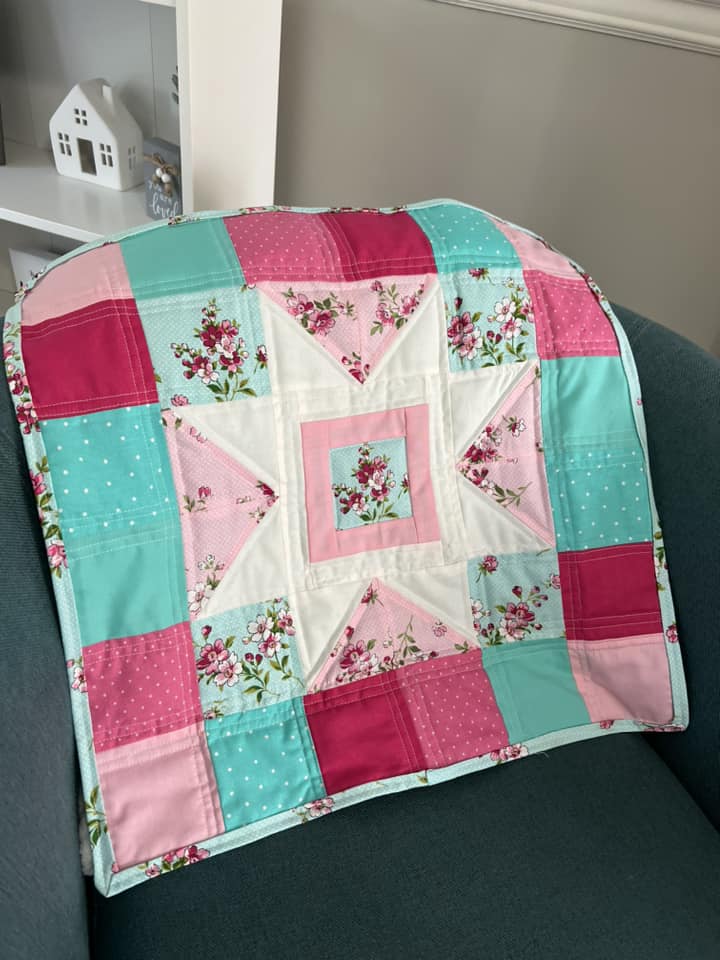 Image contains a pink and teal mini-quilt.