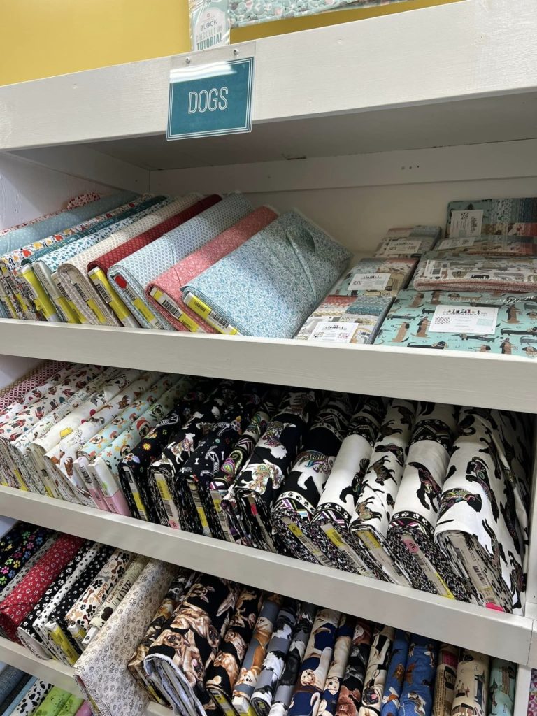 Image contains bolts of dog themed fabric in a shop.