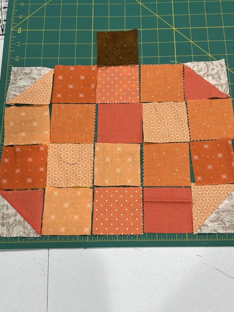 Image contains 20 orange fabric squares laid out to form a pumpkin.