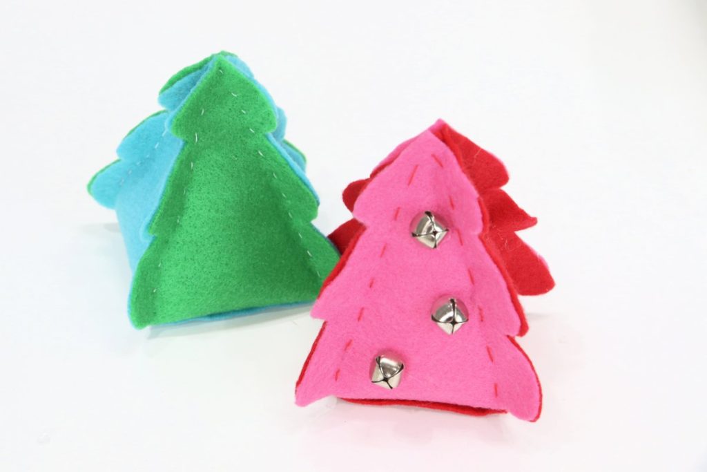 Image contains two three-dimensional felt trees. One is teal and green, and one is pink and red with three silver jingle bells.