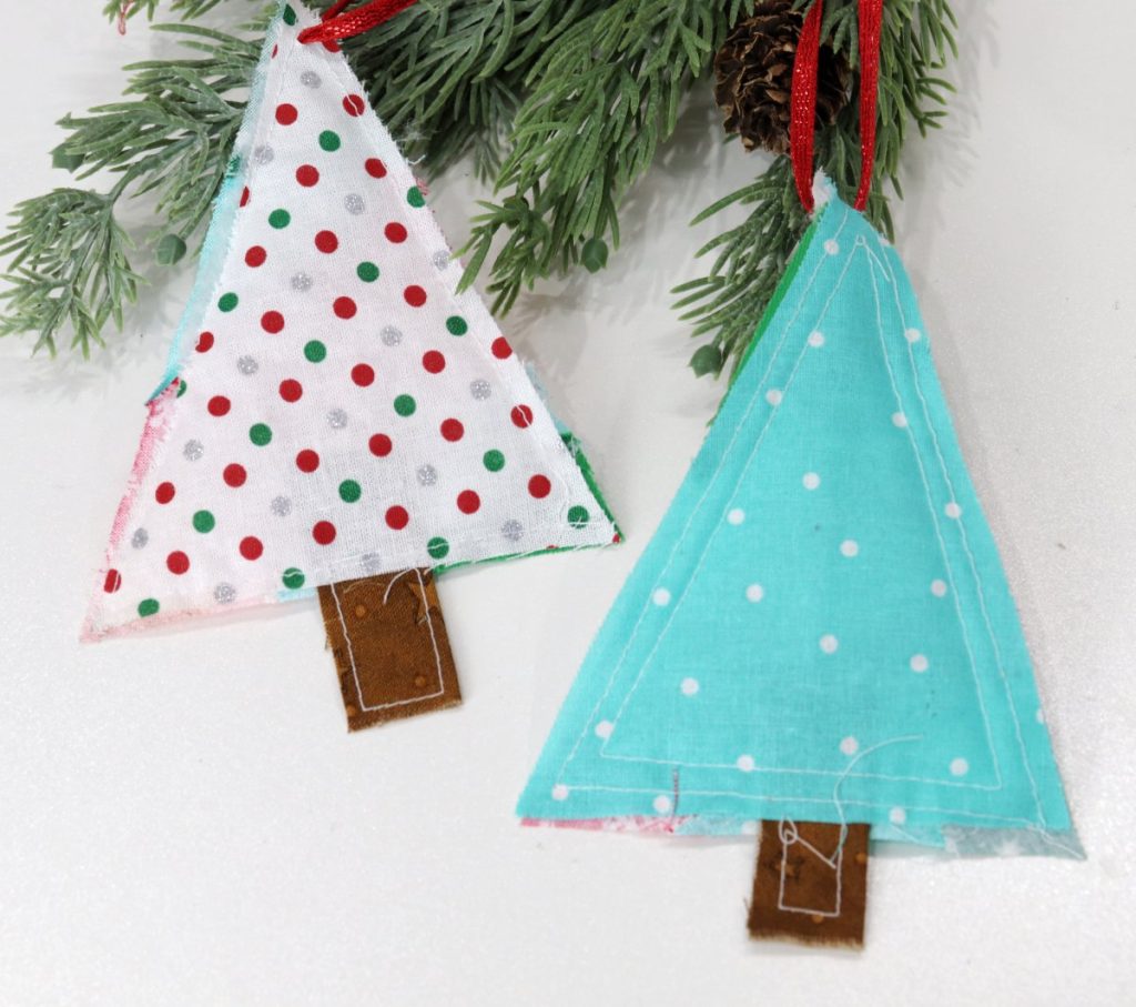 Image shows the backs of two scrappy tree ornaments; one is a white fabric with red, green, and silver dots; one is teal fabric with white polka dots.