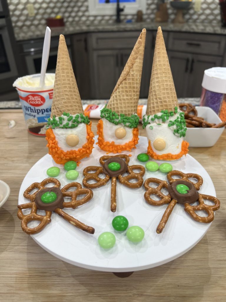 Image contains three Leprechaun Gnome snacks and three Shamrock Pretzel snacks on a round white tray.