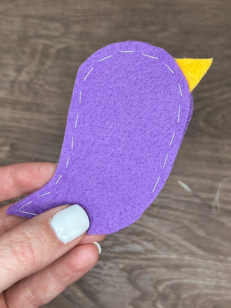 Image contains Amy's hand holding the purple felt bird hand stitched around the outer edges.