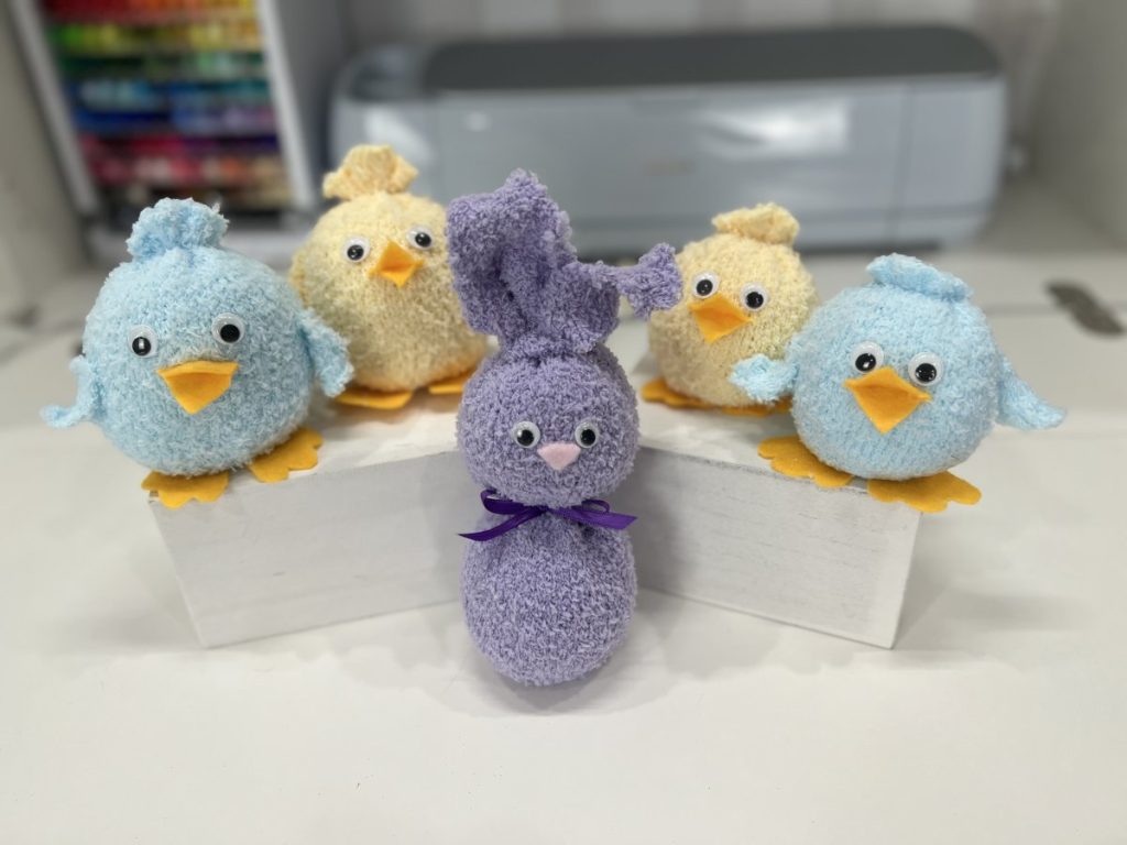 Image contains four small stuffed chicks and a stuffed bunny made from pastel colored fuzzy socks.