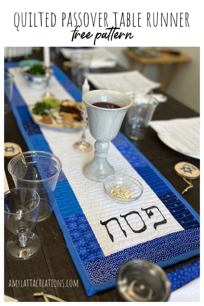 Image contains a blue and white quilted table runner on a wooden table set for the Passover Seder meal.