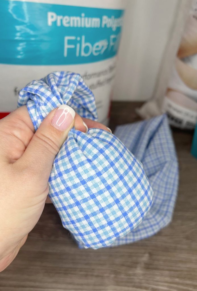 Image contains Amy’s hand holding a blue plaid fabric tube with a section filled with glasslets.