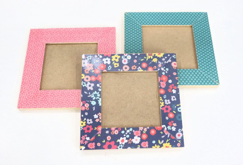 Image contains three decoupaged photo frames; one is pink, one is teal, and one is navy with multicolored flowers.