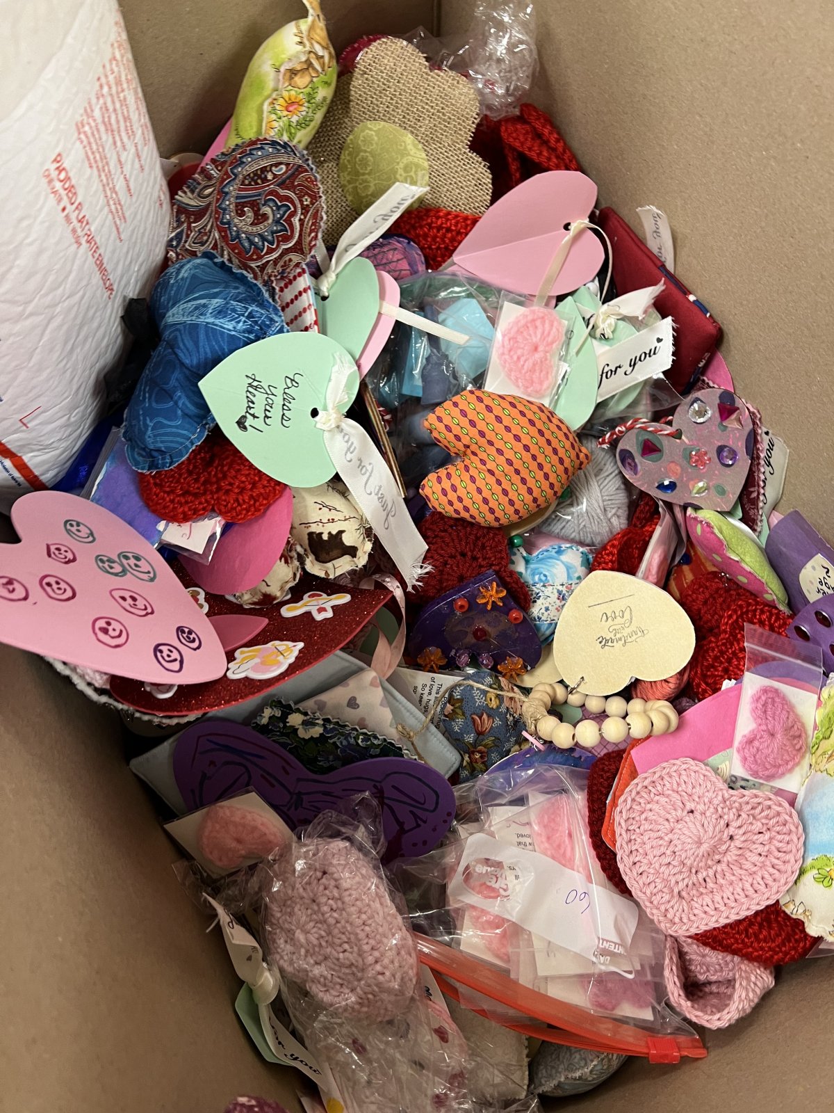 Image contains a box filled with a huge variety of handmade hearts.