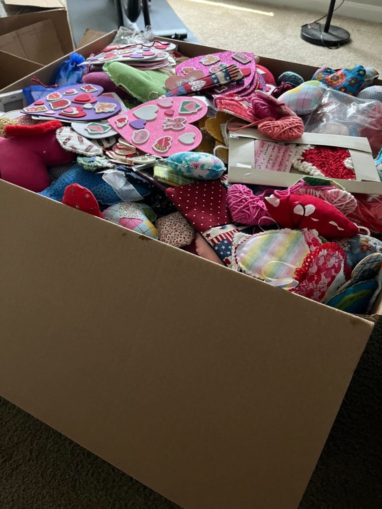 Image contains a large cardboard box overflowing with handmade hearts.