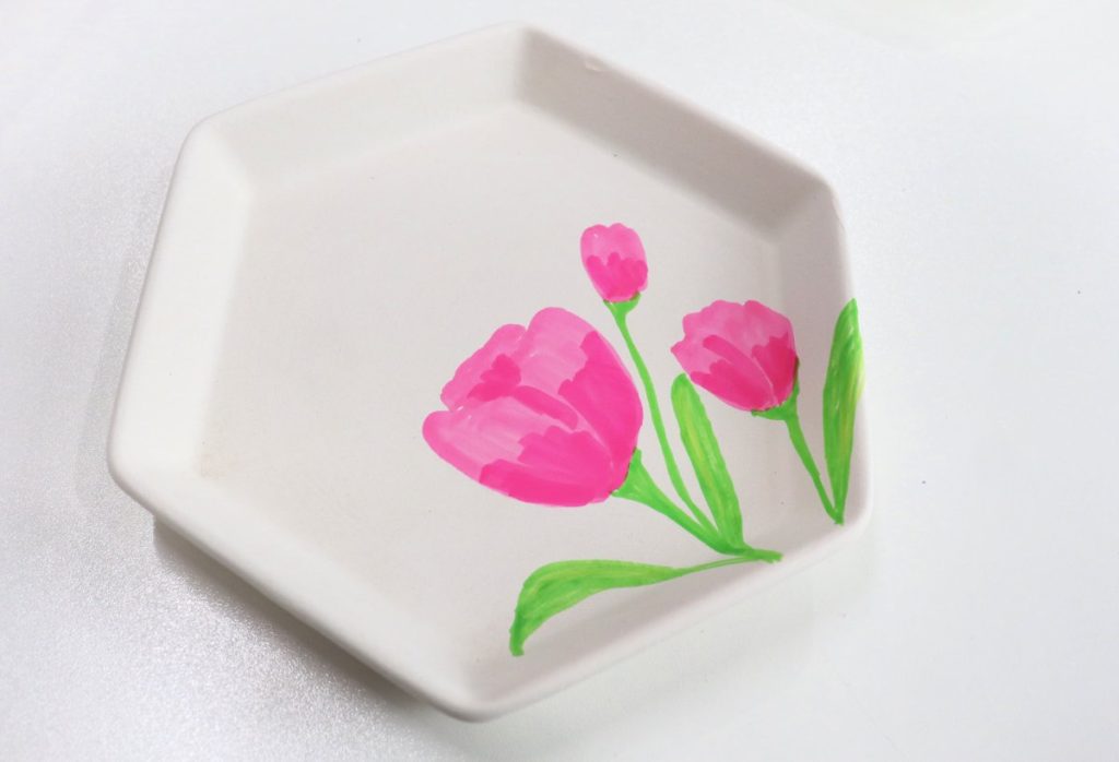 Image contains a white jewelry tray with three pink tulips, with stems and leaves drawn on it.