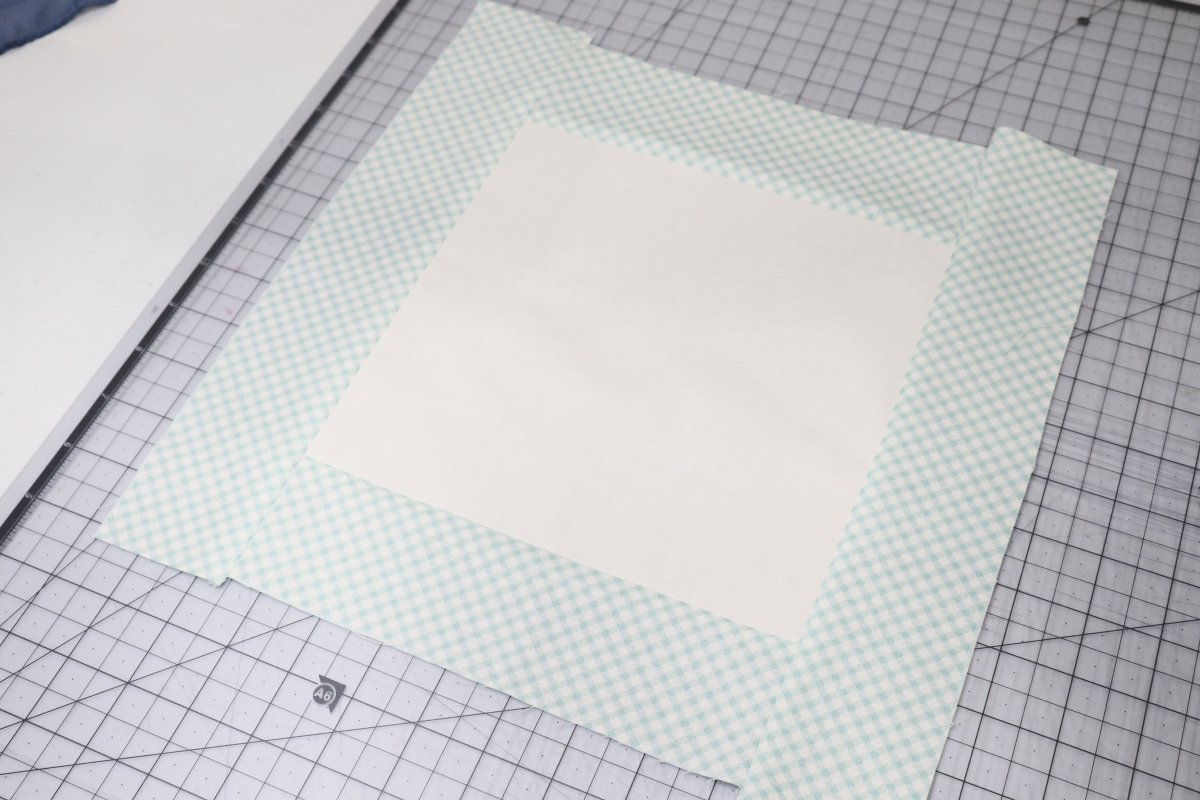 Image contains a white fabric square with blue and white print sashing.
